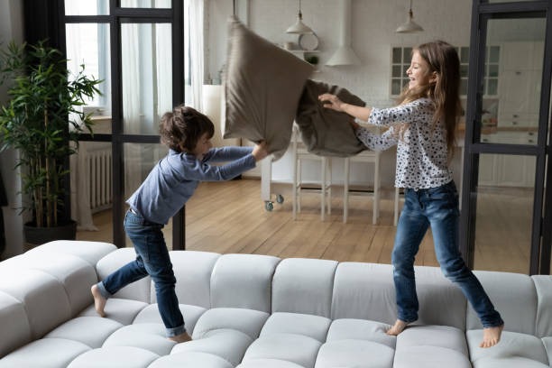 Dos niños teniendo una pelea de almohadas en el sofá