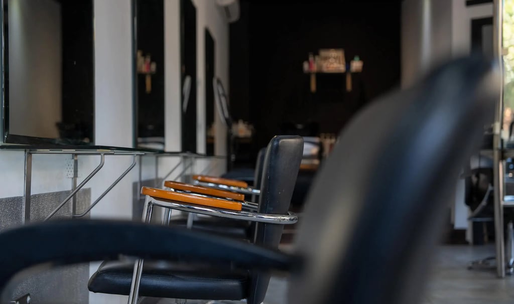 Modern hair salon interior featuring black styling chairs and minimalist mirrors.