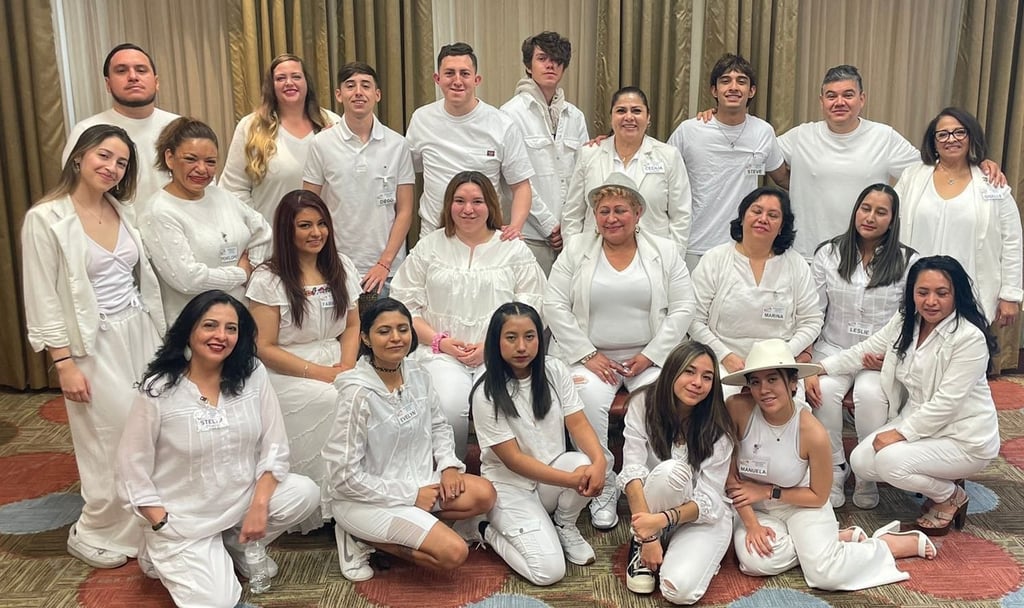 A large group of people posing for a photo wearing all-white clothing at a formal gathering.