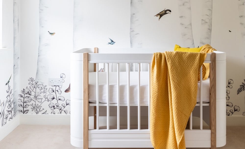 a baby's nursery with a beautiful jungle themed wallpaper 