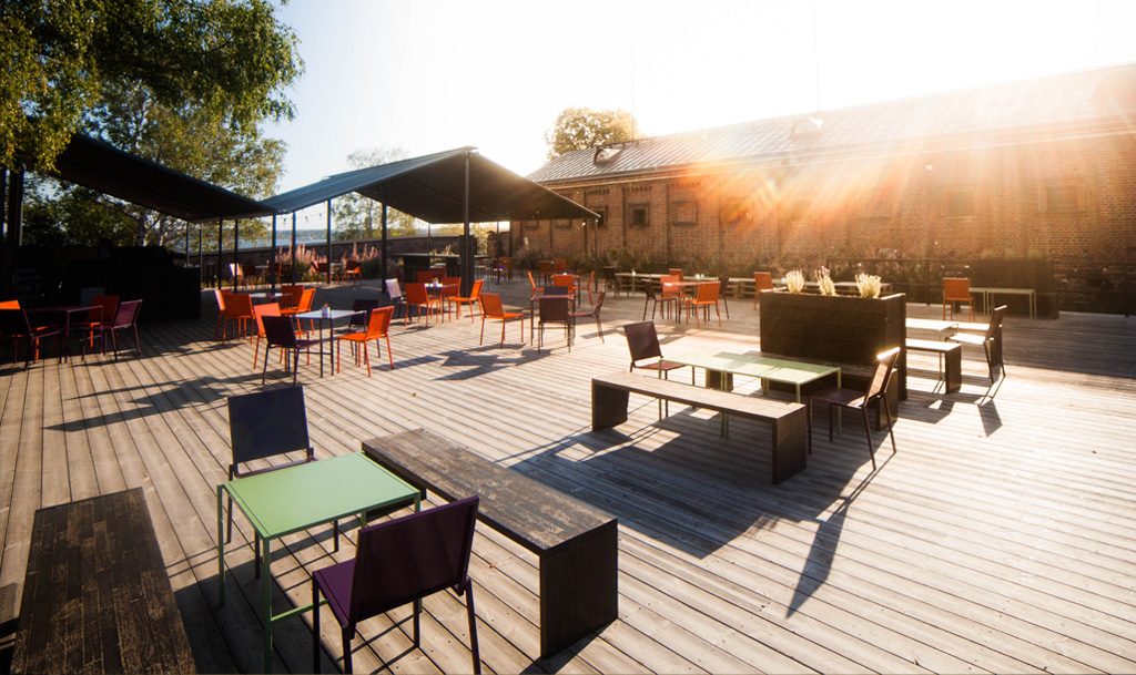 a wooden deck with chairs and tables in the sun