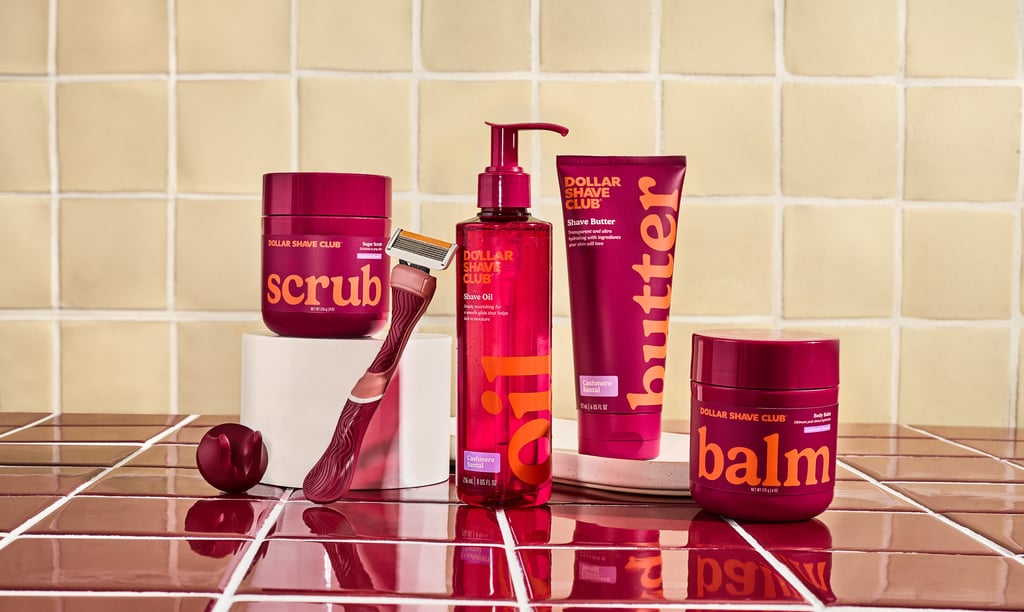 Dollar Shave Club men's grooming kit with razor, scrub, shave butter, oil, and balm on a tiled background.