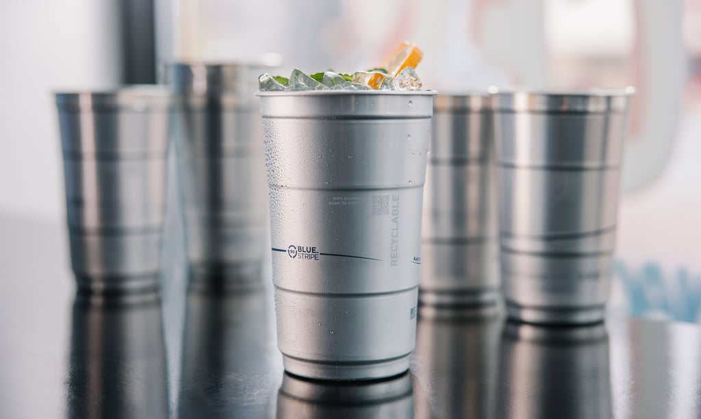 A chilled recyclable aluminum cup filled with an iced cocktail and fresh mint garnish.