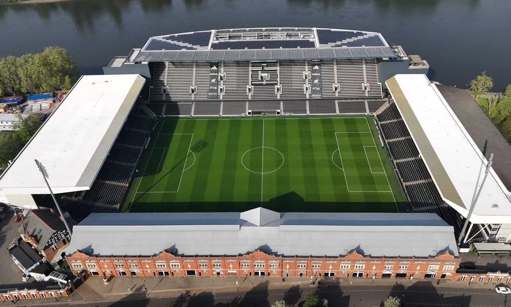 Vogelperspektive auf Craven Cottage, das Heimstadion von Fulham FC in London, mit Tribünen, Spielfeld und Themse im Hintergru