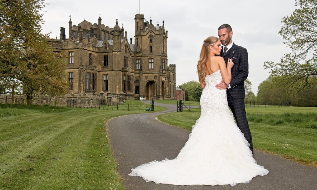 bride and groom stood in a dramatic pose into front go a grand castle