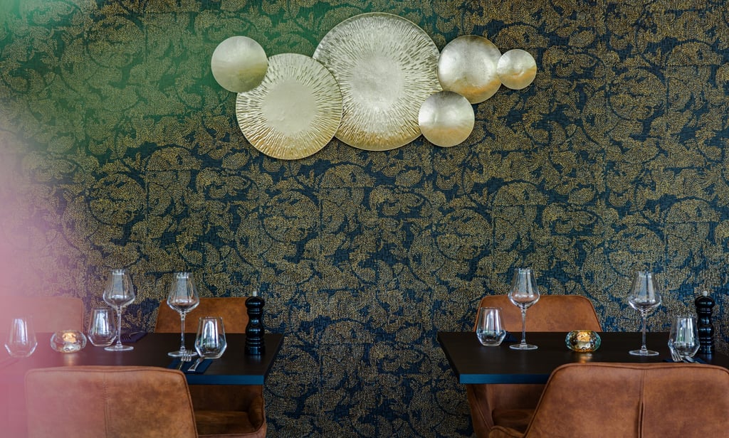 Elegantes Fine-Dining-Restaurant-Interieur mit goldener Wandkunst und braunen Lederstühlen