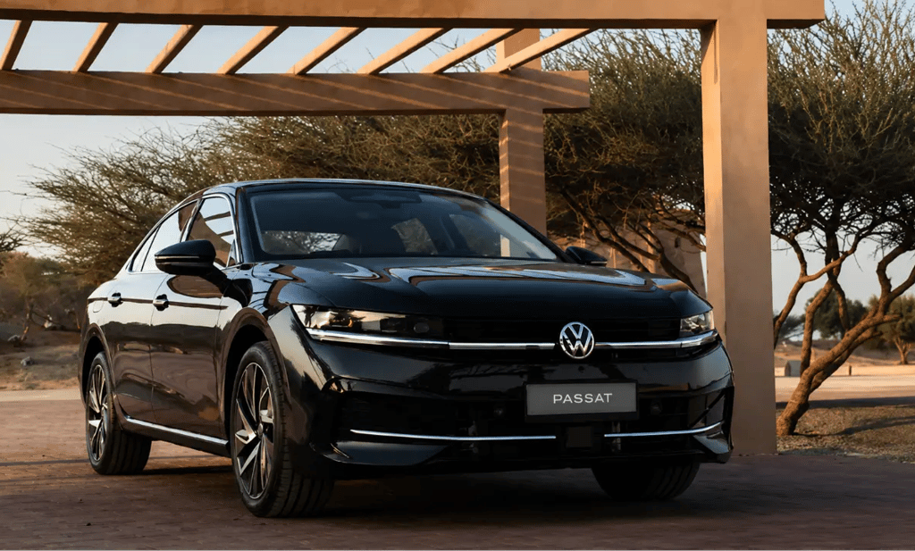 Volkswagen Passat Sedan preto em estrada desértica ao entardecer.