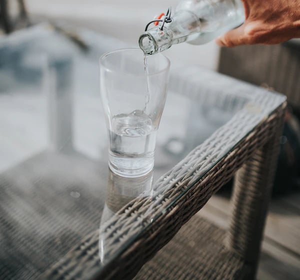 a person pouring water into a glass of water