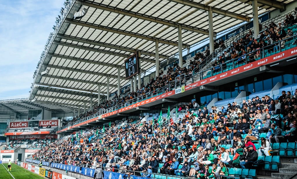 Fans von FC Flora Tallinn in grün-weißen Farben stehen dicht gedrängt auf der Tribüne und feuern ihr Team mit Fahnen
