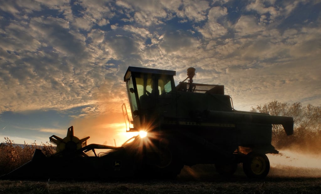a tractor driving through the field with the sun shining