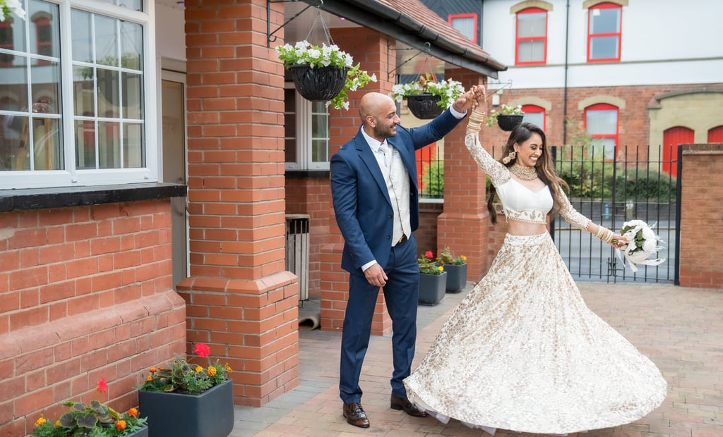 asian bride and groom dancing and both smiling, wall framing them 