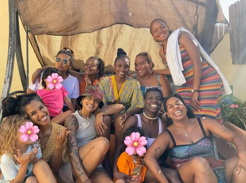 Un grupo de mujeres africanas y afrodescendientes celebrando sentadas en un balancin