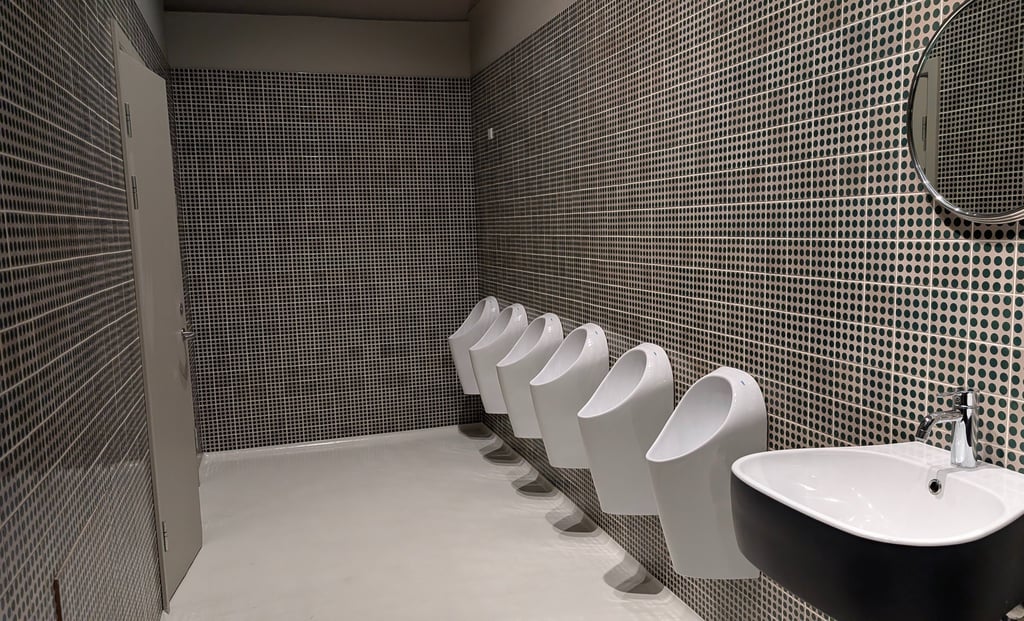 Modern unisex restroom interior—minimalist design, open space, six urinals visible