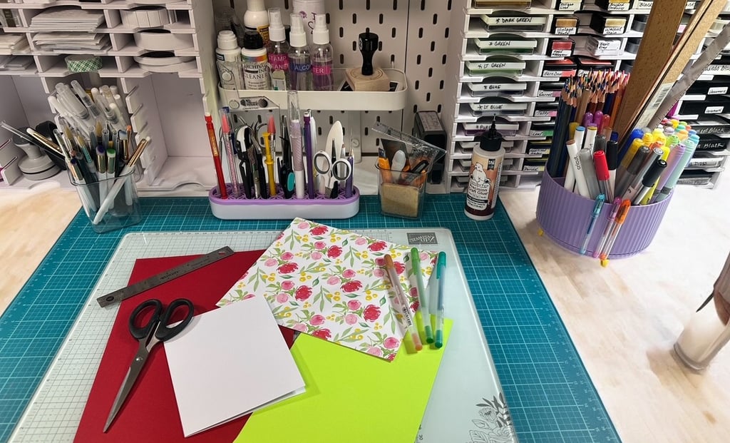 Desk with a variety of craft tools, paper, scissors, ruler and various writing tools. 