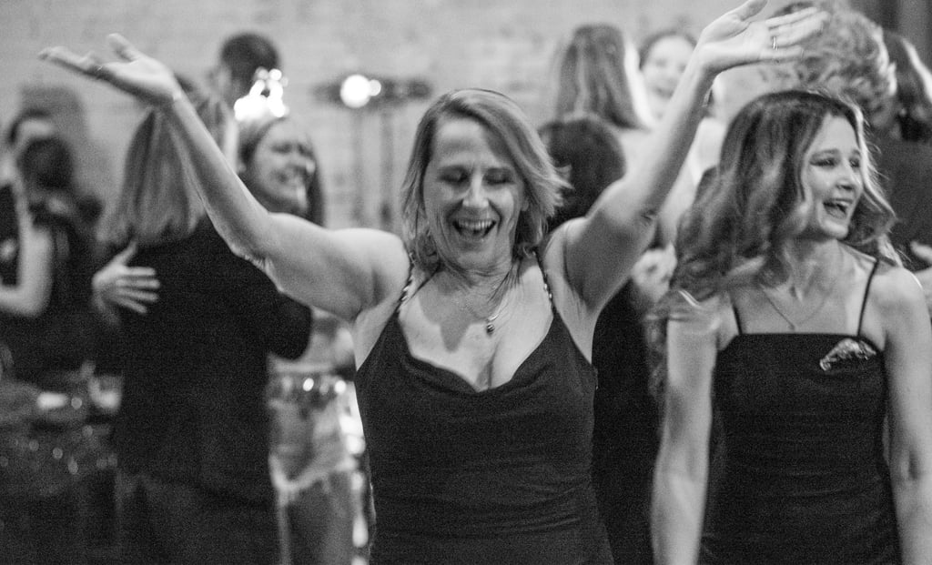 A cheerful woman dancing with arms raised during a gala in downtown Austin