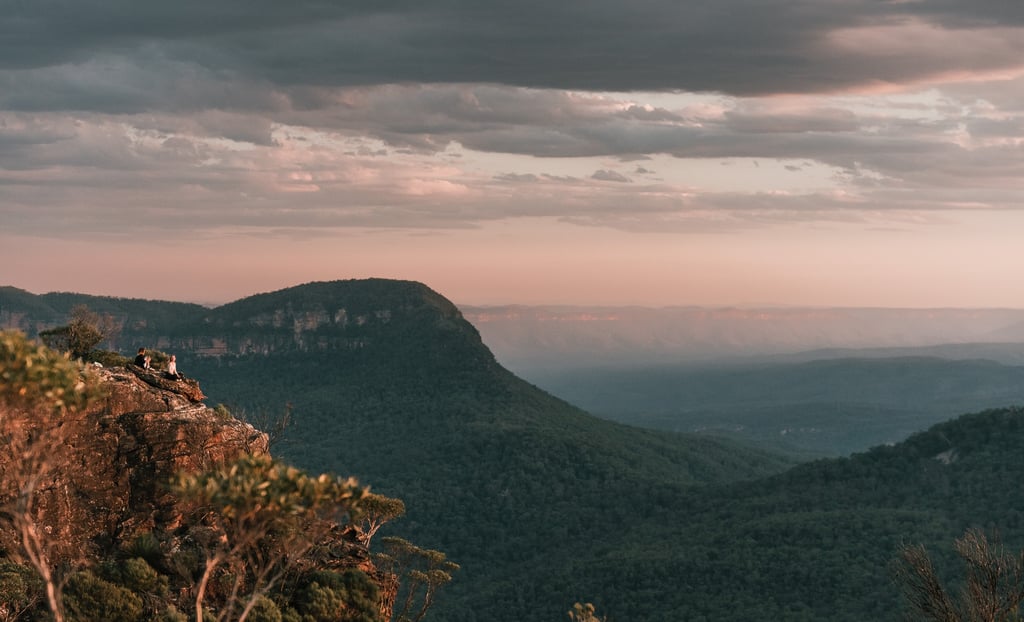 a person sitting on a mountain top with a view of the mountains
