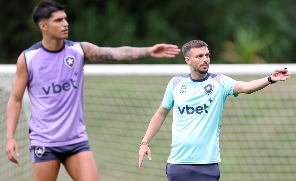 Botafogo soccer coach directing a training session with players on a grass field.