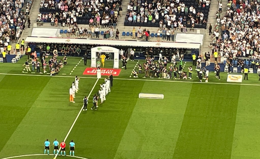 Innenansicht des Estadio Santiago Bernabéu während eines Spiels, mit voll besetzten Tribünen und Fans.