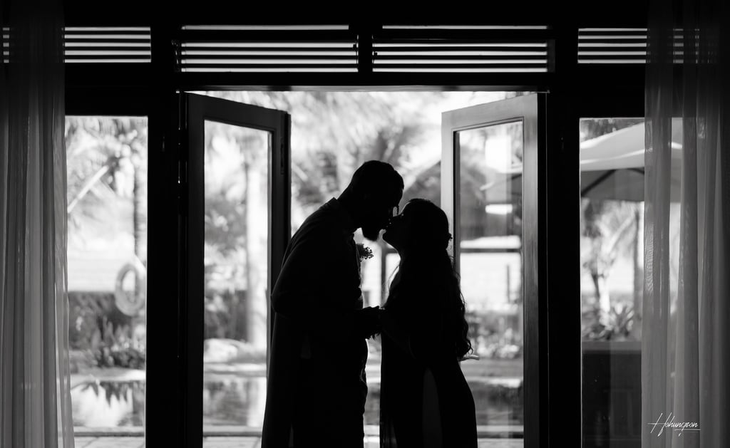 a couple kissing in front of a large window