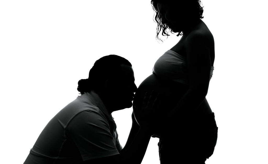 a pregnant woman is holding her belly while a man is kneeling down