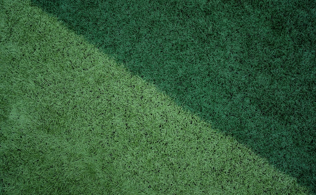 Diagonal split between light and dark green artificial turf, showcasing distinct textures for sports fields or landscaping.