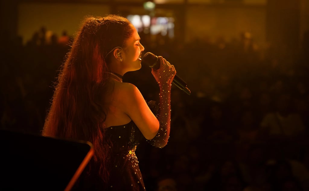 a woman in a black dress singing into a microphone