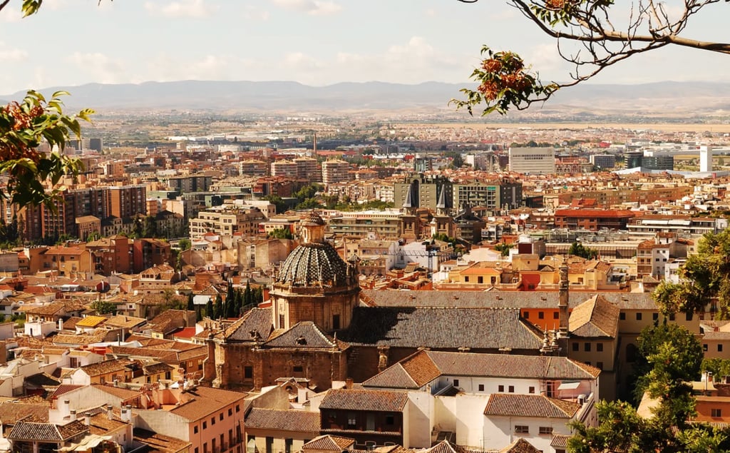 Panoramic cityscape view of Granada, Spain featuring historic tiled roofs and the domed Parroquia de los Santos Justo y