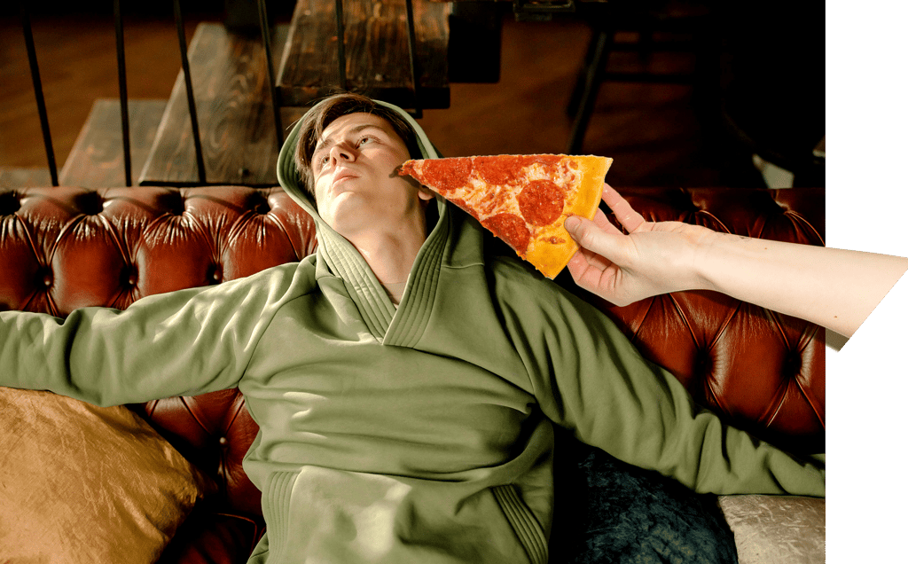 Verveelde jonge man op bank krijgt pizza aangereikt