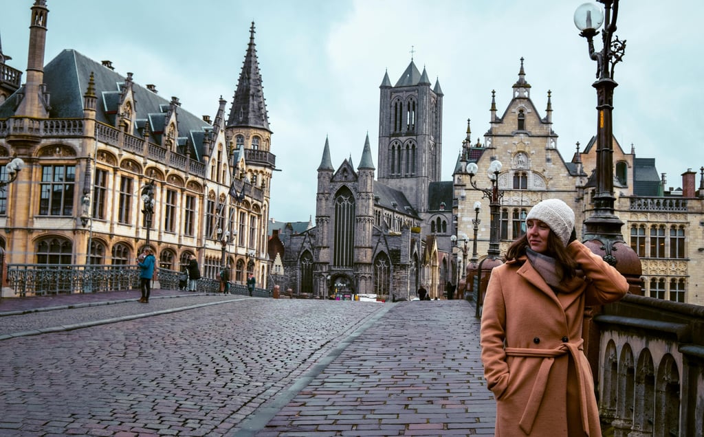 A woman in coat leaning on the wall in Ghent