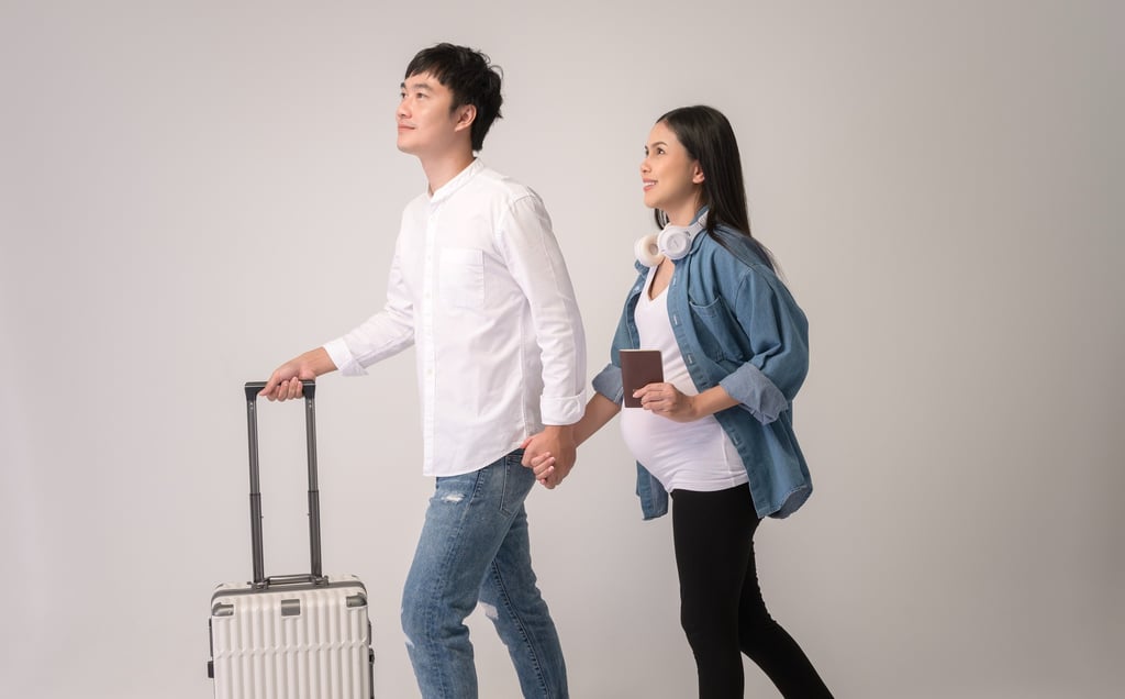Pregnant couple with suitcase at airport