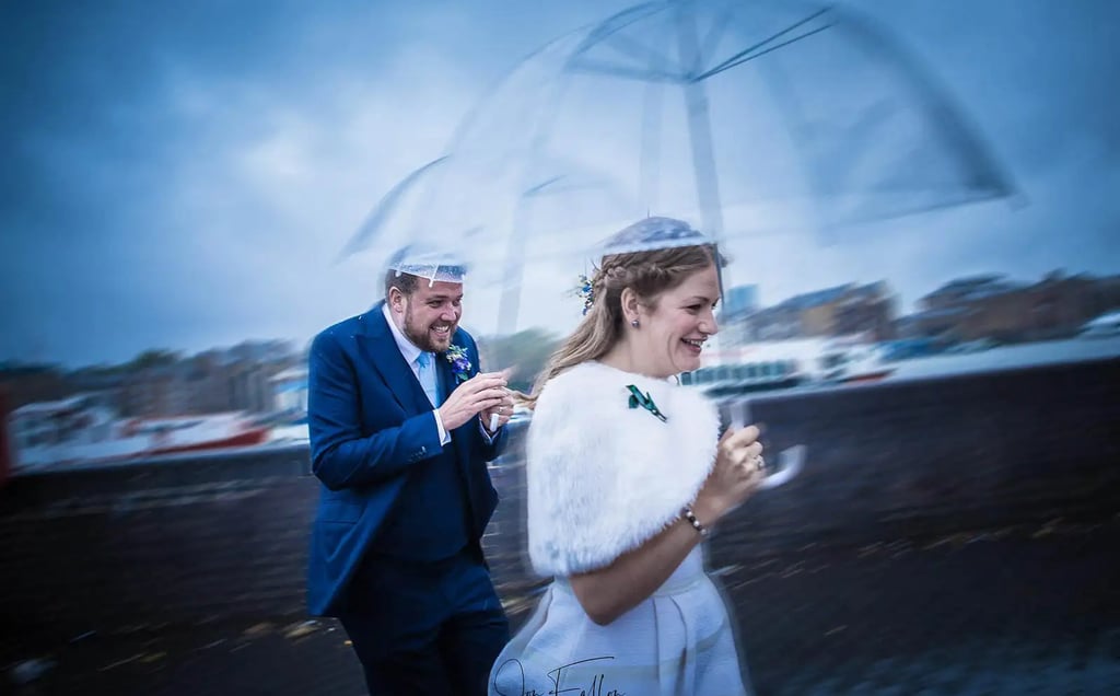 wedding couple with umbrellas running from the rain