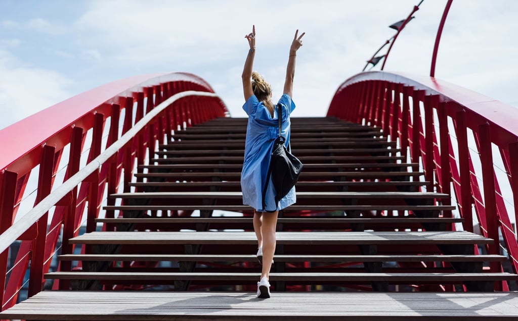 a woman in a blue dress standing on a bridge