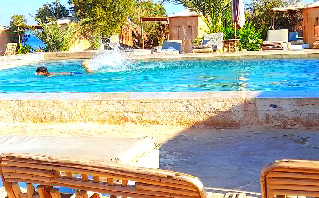 Junge schwimmt im Pool in der Nähe des Meeres und Bungalow im Beduinenstern Ägypten