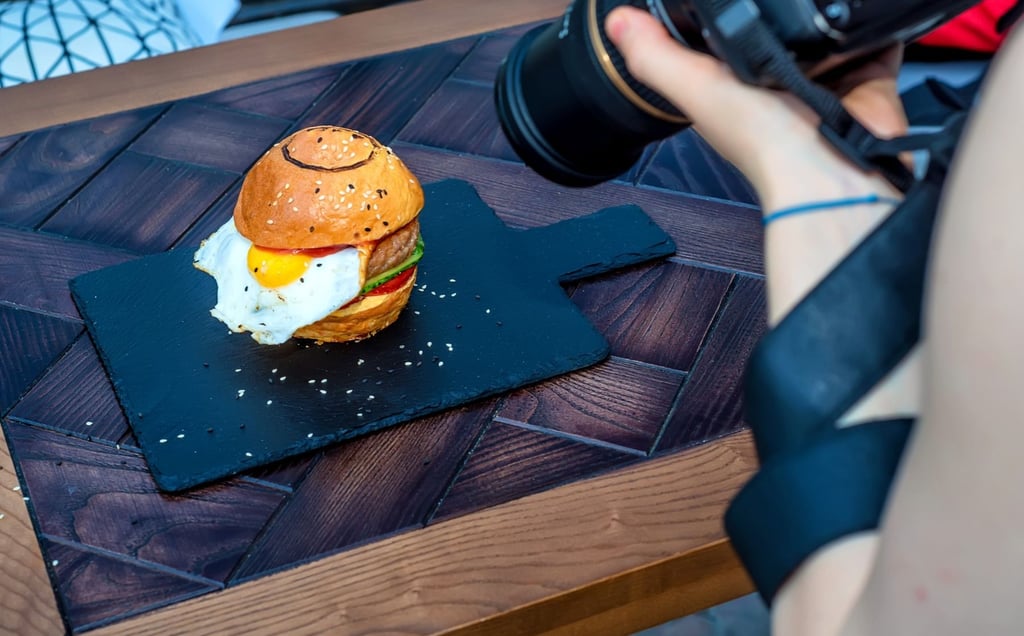 Un photographe prend une photo d'un burger sur une ardoise