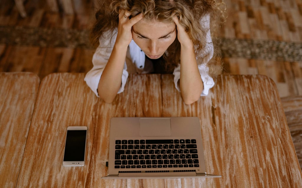 a woman sitting at a table with a laptop and a cell phone