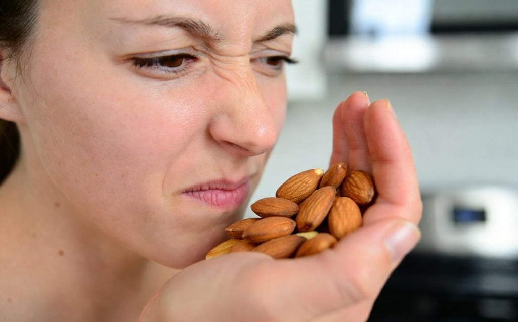 Persona oliendo un puñado de almendras con expresión de duda, realizando el test sensorial de frescura