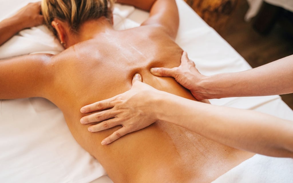 Masaje relajante de espalda aplicado manualmente sobre paciente tumbado boca abajo.