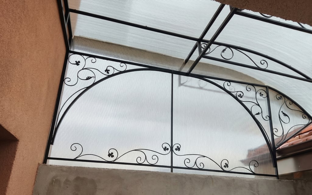 Custom decorative wrought iron balcony railing with a polycarbonate canopy roof for outdoor weather protection.