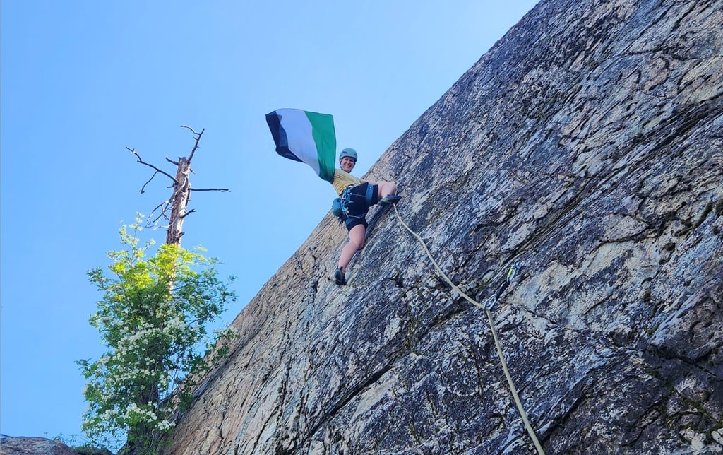 A climber halfway up the wall waving a Palestinian flag