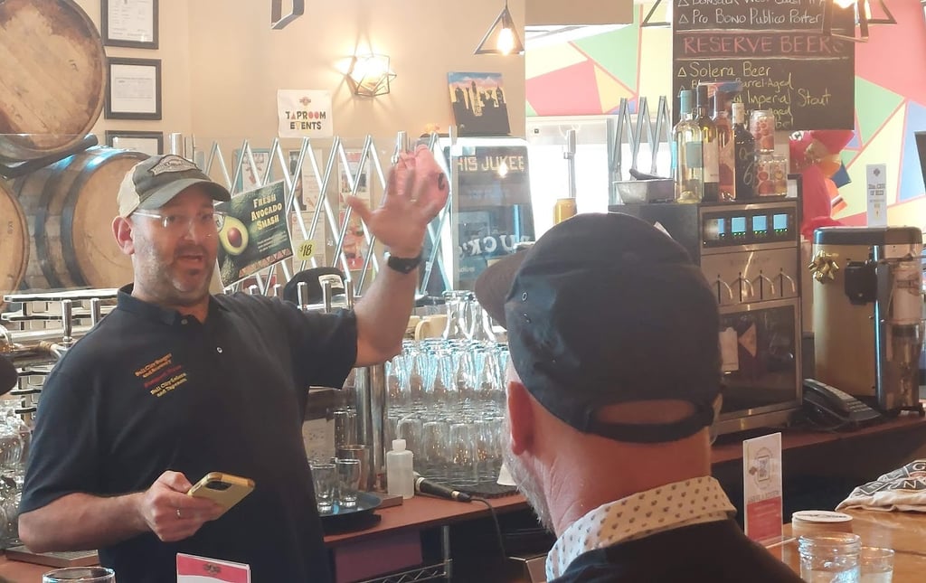 Seth Gross talking in front of an arrangement of barrels and glassware