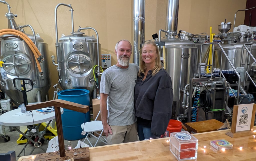 michael and kathleen cherry standing in front of brewing tanks