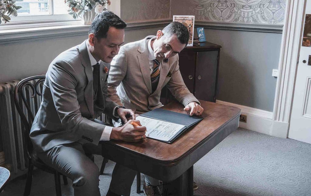 two grooms signing the wedding register