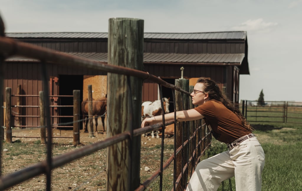 a woman leaning on a fenced in area with a horse
