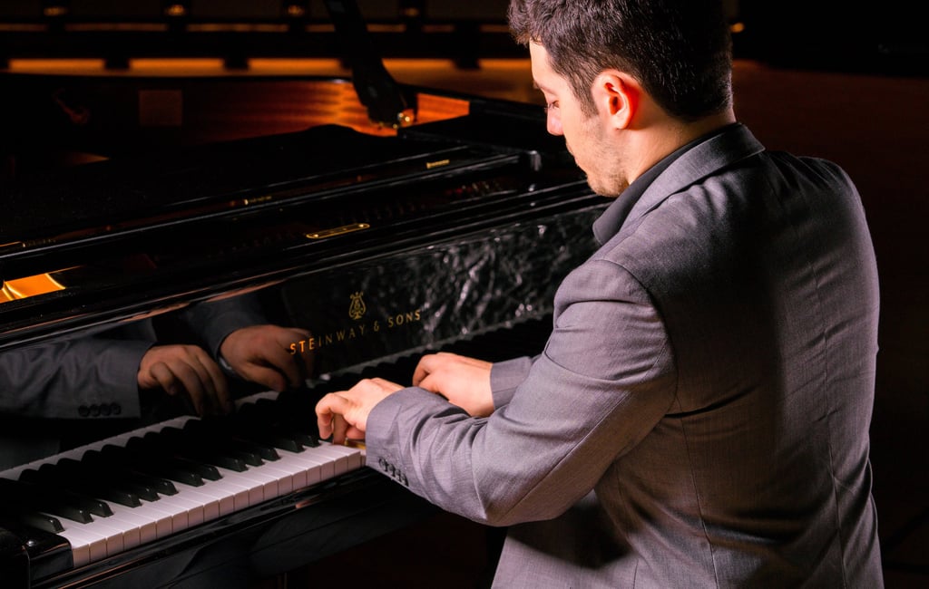 Stathis Chomatsas playing piano in a concert hall during a photoshoot