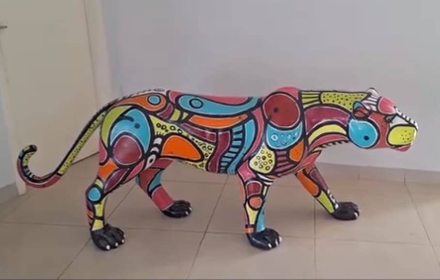 Detalhe da escultura de onça pintada com padrões gráficos vibrantes por Aloísio Marinho