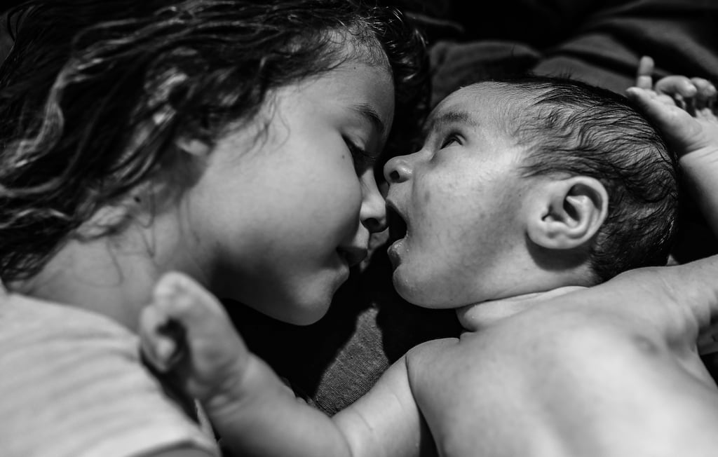 a baby is kissing her sister's face