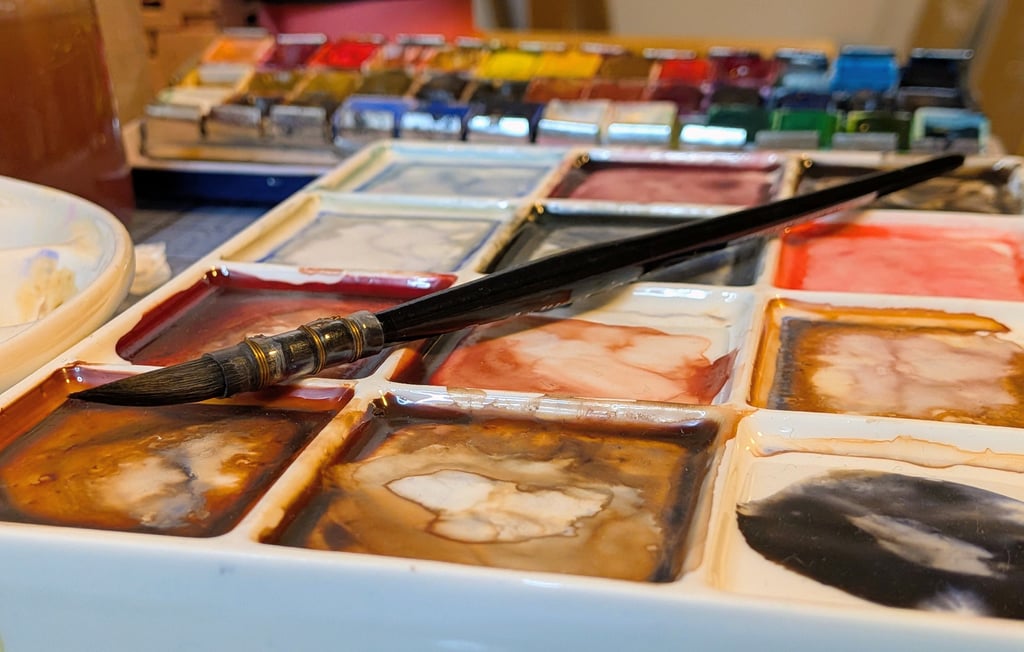 Waterverf palet met penseel en aquarel napjes, gemengde kleuren op een bord