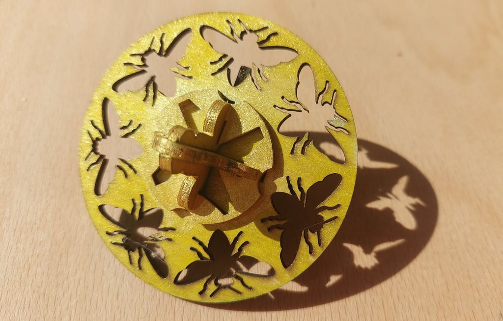 Wooden spinning top painted yellow with bee cut outs