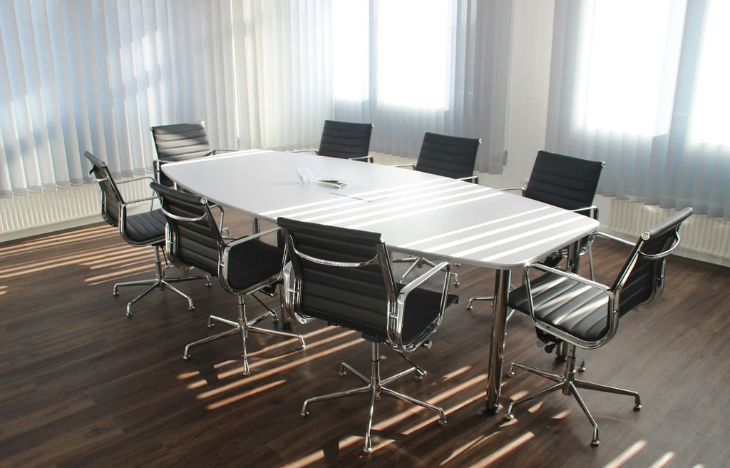 Modern meeting room with white conference table and black chairs