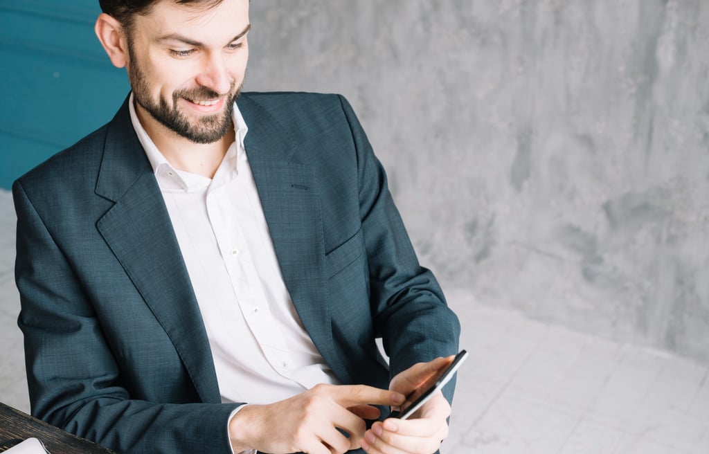 Advogado sorridente, usando terno e olhando o seu celular enquanto utiliza o Instagram